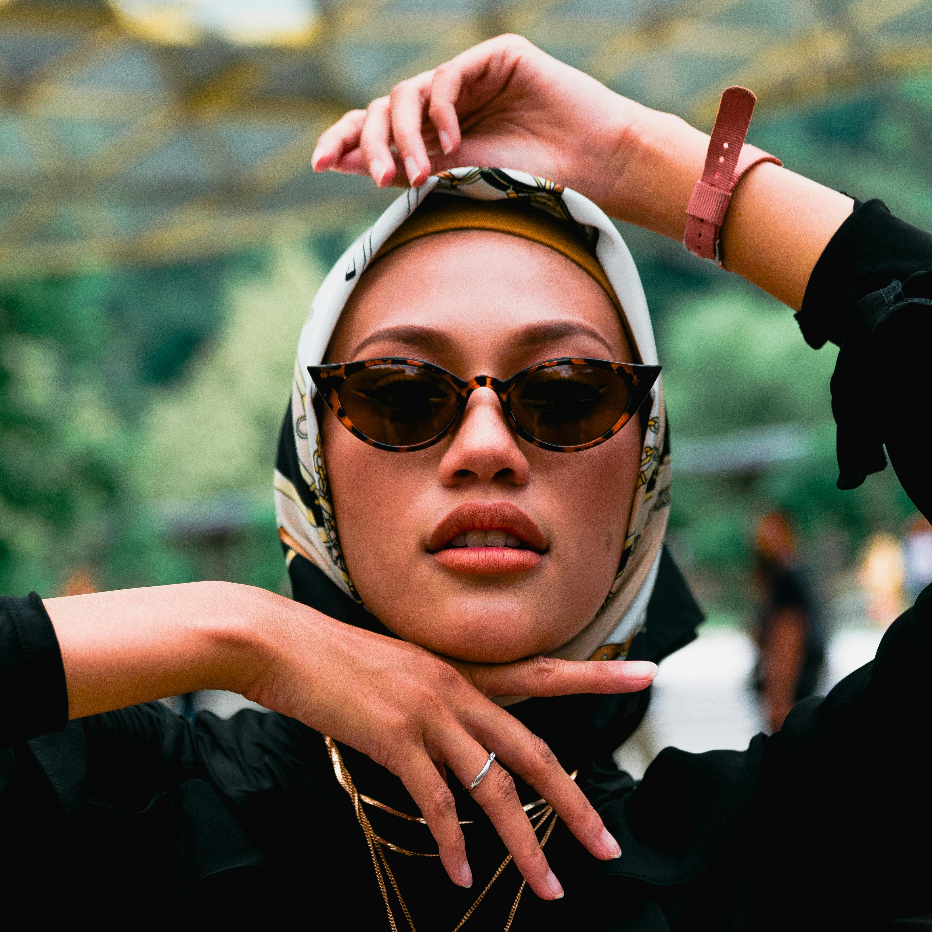 Elegant woman wearing a hijab and sunglasses, posing with flair in an outdoor setting.